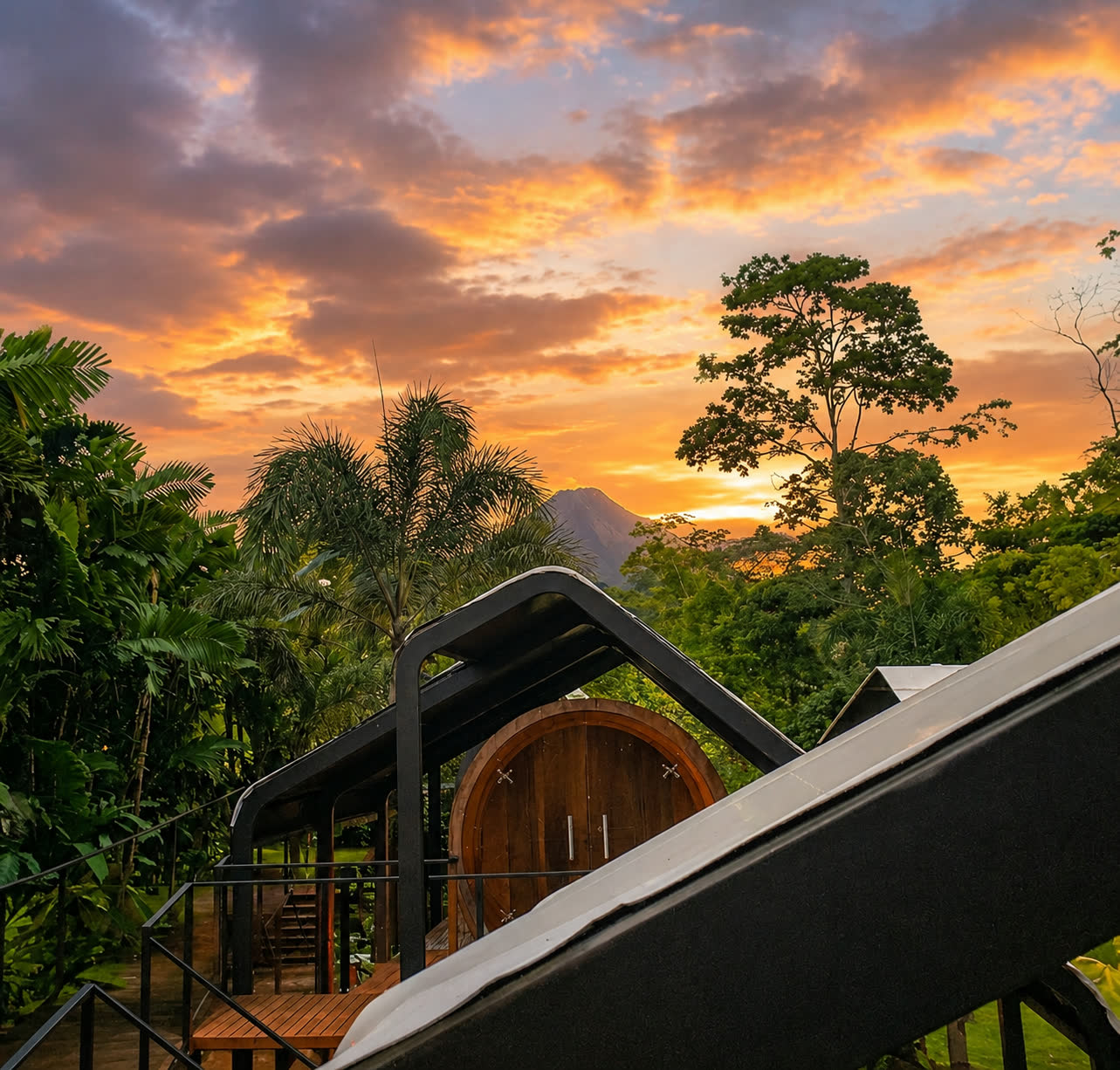Cylinder rooms surrounded by tropical gardens with Arenal Volcano at sunset