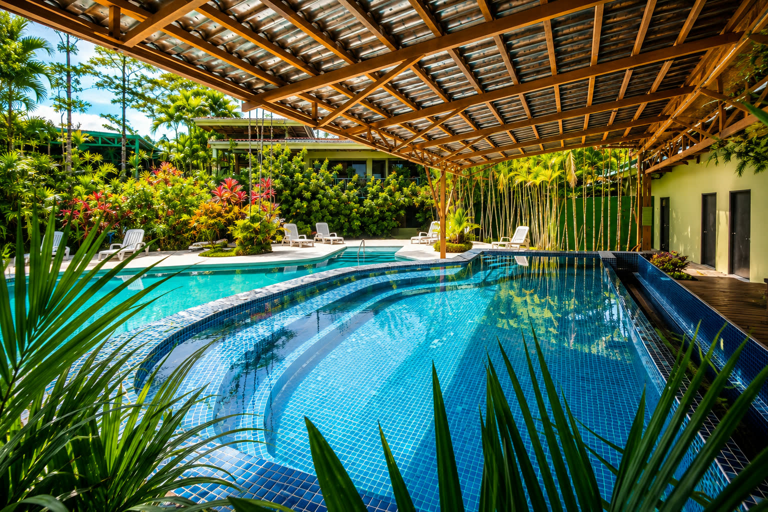 Outdoor pool surrounded by tropical gardens at Arenal Backpackers